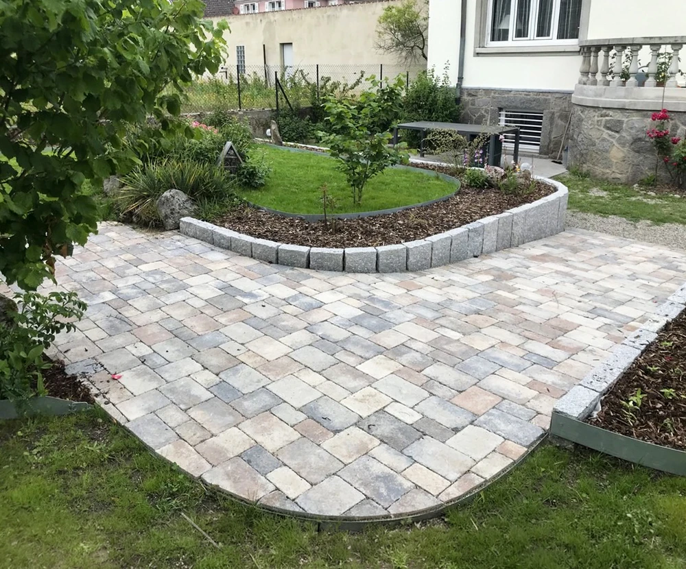 Jardin extérieur avec bordures en pierres naturelles délimitant des espaces de plantation