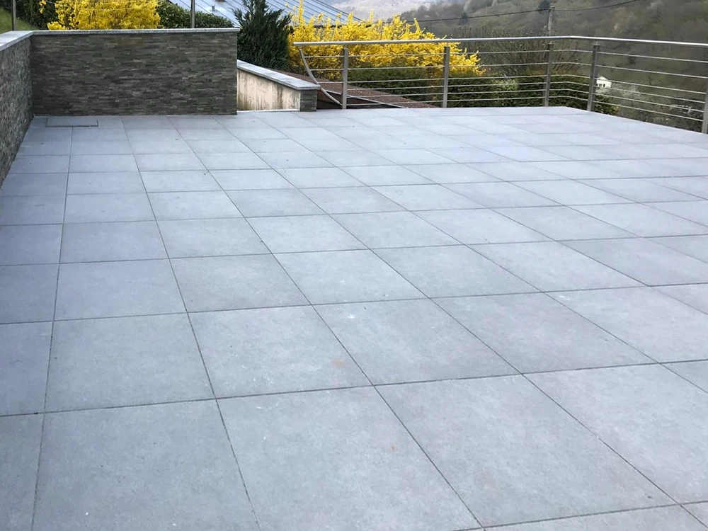 Terrasse extérieure aménagée avec salon de jardin en résine tressée, parasol vert lime, table ronde métallique et barbecue
